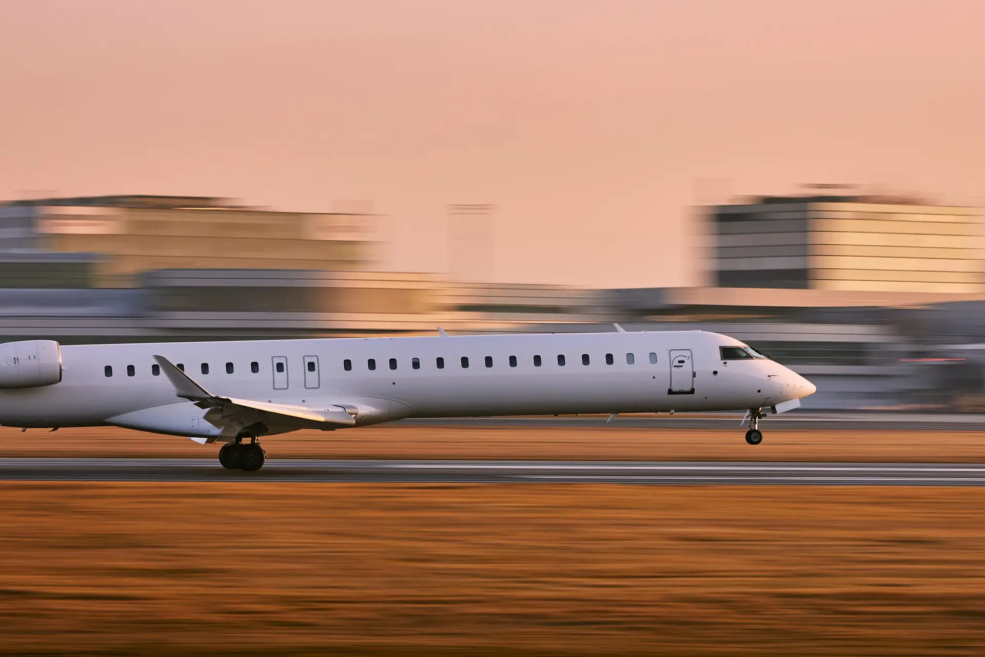Small white jet landing at an airport. Background is blurred to reinforce the sense of motion