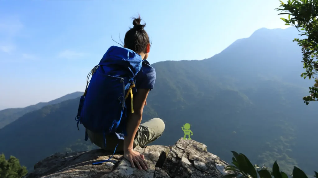 Woman hiker sitting that the summit of a moutain looking at the view with a cute robot beside her pointing in the distance
