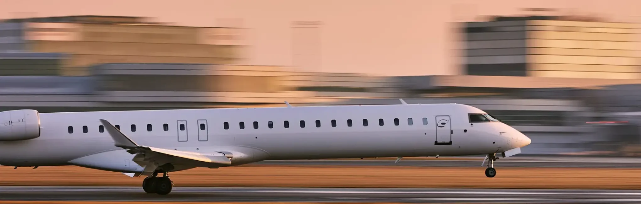 Small white jet landing at an airport. Background is blurred to reinforce the sense of motion